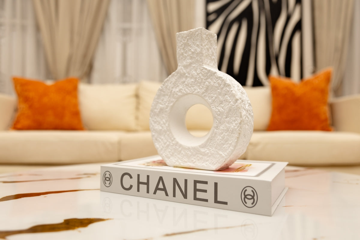 White textured vase on a chanel book, modern interior.